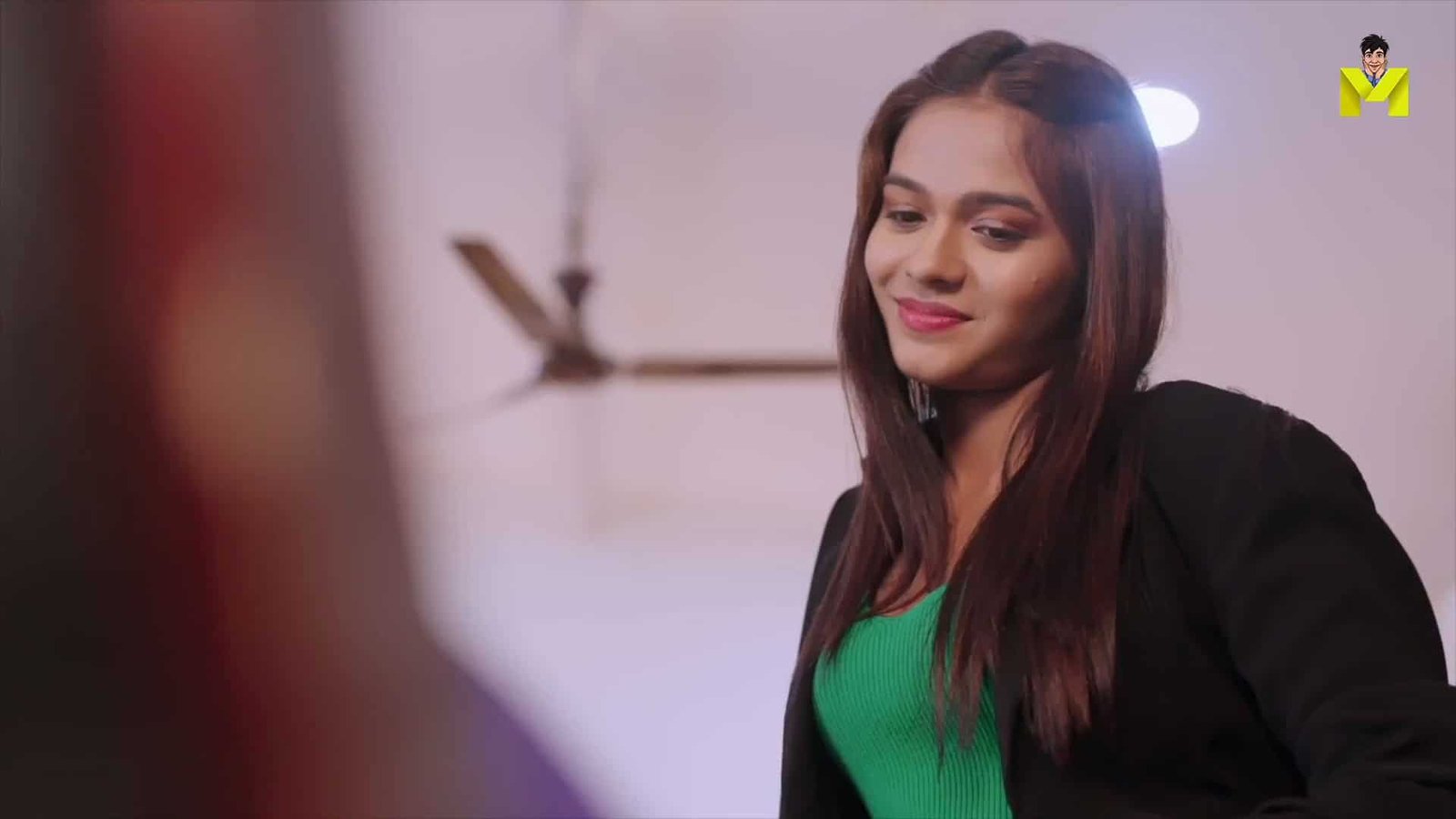 Beautiful woman with long brown hair wearing a green top and black jacket.