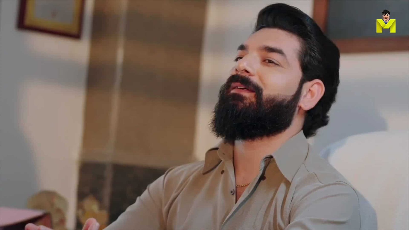 Handsome man with beard relaxing in a cozy room, dressed in a beige shirt.